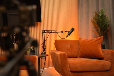 Sofaopstelling vanuit vogelperspectief met twee oranje stoelen, microfoon en warme verlichting