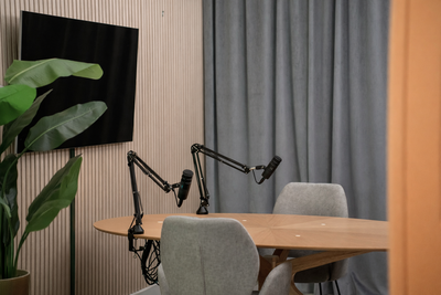 Opnameruimte met professionele microfoons, ronde houten tafel en oranje accentverlichting